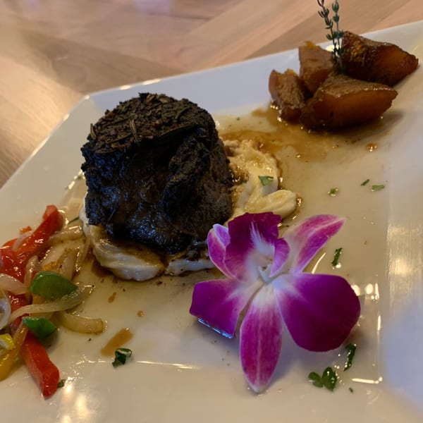 IXCHEL Mexican Cuisine's mole-crusted steak, mashed potatoes, bell peppers, and plantains, garnished with an orchid.