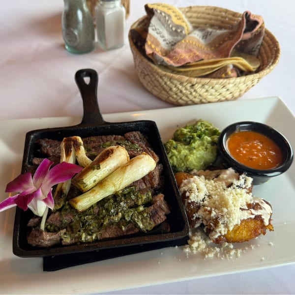 IXCHEL Mexican Cuisine's sizzling steak with grilled green onions, guacamole, salsa, and plantains.