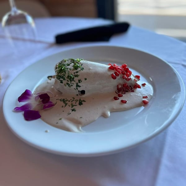Chiles en Nogada, a Mexican dish, garnished with pomegranate seeds, parsley, and an orchid.