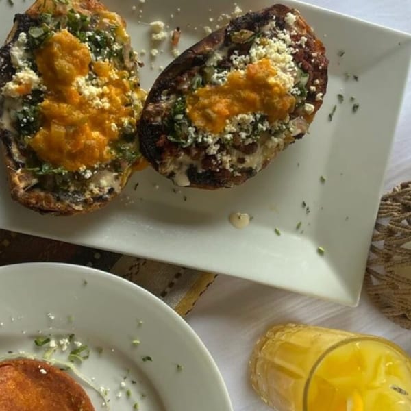 Two stuffed Mexican dishes with orange sauce and crumbled white cheese on a white plate.