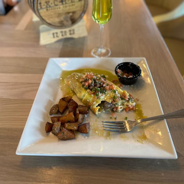 A Mexican omelet with salsa, green sauce, and roasted potatoes on a white plate.