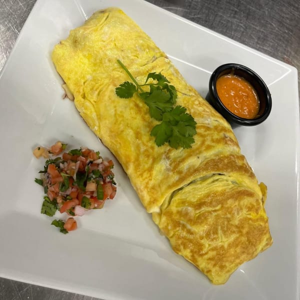 A Mexican omelet garnished with cilantro, served with pico de gallo and a side of red sauce.