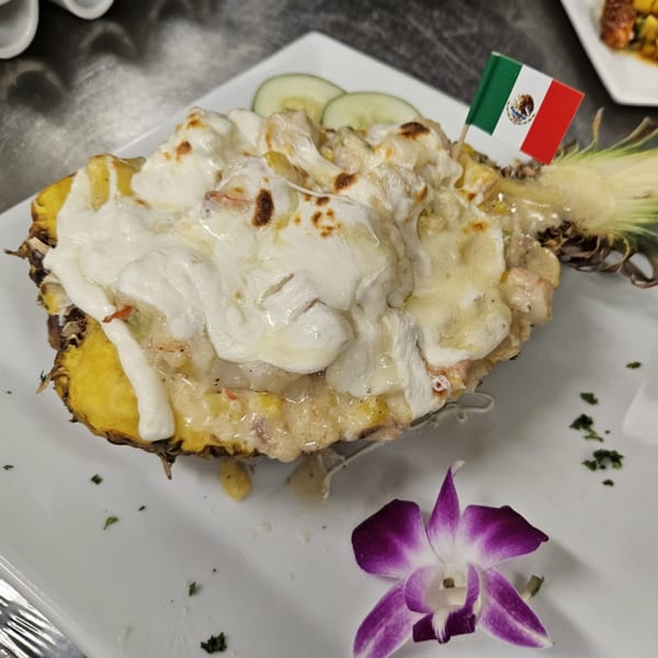 IXCHEL Mexican Cuisine's pineapple dish, topped with melted cheese and a small Mexican flag.